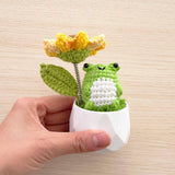 Holding the crochet frog and sunflower pot