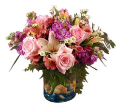 Beach themed flower arrangement of pinks, peaches and purples in cylinder vase with shells
