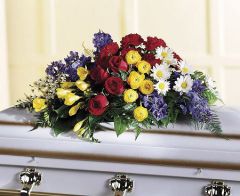 Floral oasis casket spray with bold red, blue and yellow flowers