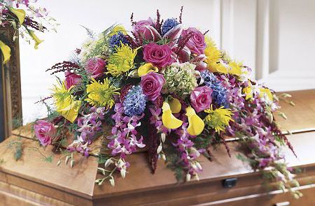 Funeral casket spray of purple, yellow and green flowers
