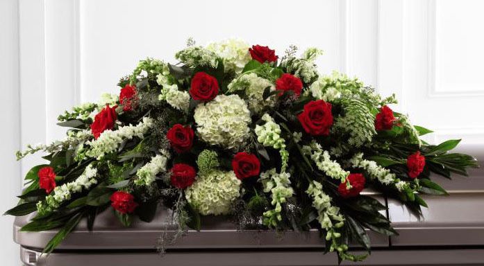 Funeral flower casket spray of red roses with assorted green flowers Small