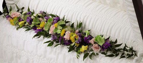 Trail of flowers casket adornment of pinks, yellows and purples