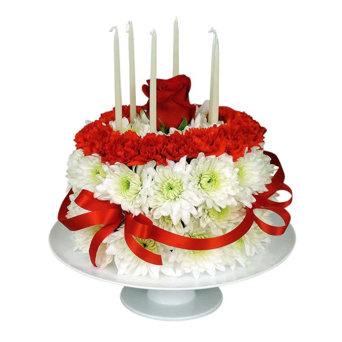 Floral birthday cake on stand with candles