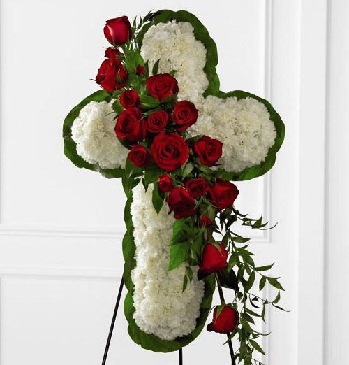 Funeral flower cross on stand with white carnations and red roses